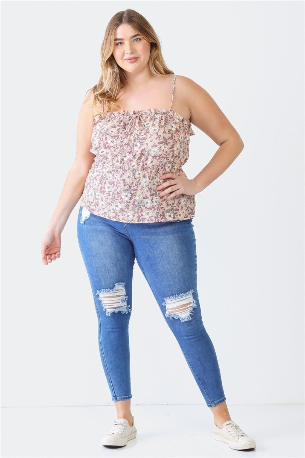 A person with long hair, wearing the Zenobia Plus Size Frill Floral Square Neck Cami and dark jeans, stands with one hand on their hip and the other relaxed by their side.