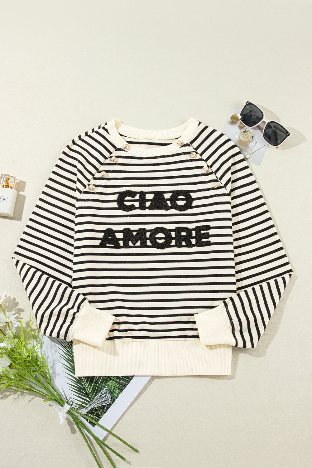 A person with long hair is facing away, wearing a Black Stripe CIAO AMORE Graphic Buttoned Pullover Sweatshirt and a black skirt in an indoor setting. The shirt subtly whispers "CIAO AMORE.