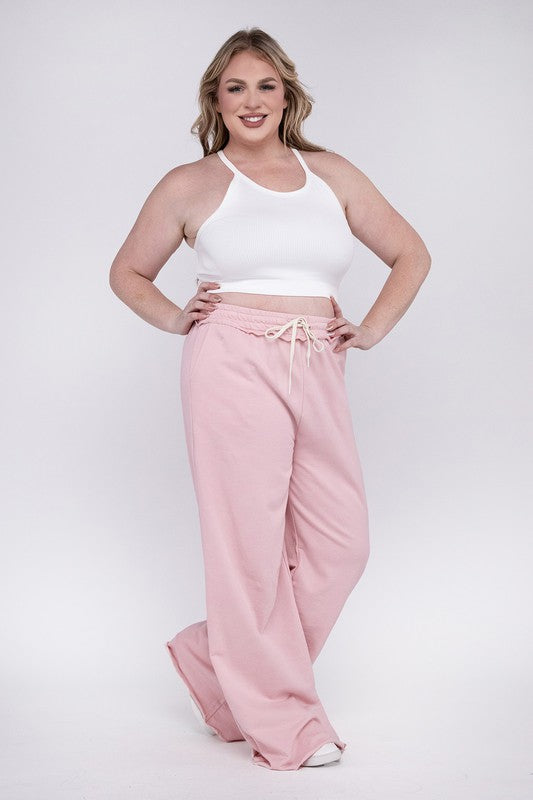 A person wearing the Plus F/Terry Drawstring Waist Raw Edge Hem Pants in pink, paired with white shoes, stands against a plain background.