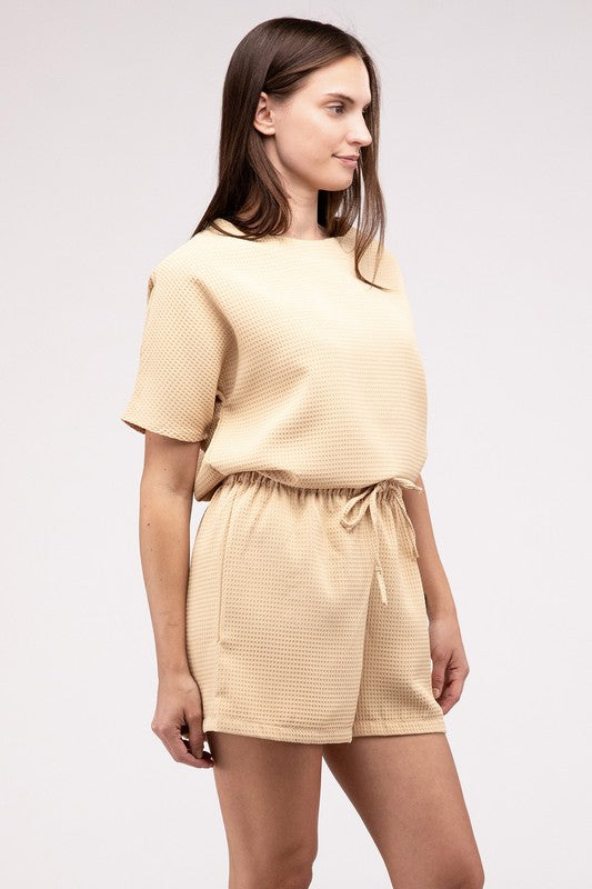 Clad in the Waffle Round Neck Top and Short Set paired with black sunglasses, a person stands against a plain beige background, highlighting the non-stretch polyester fabric.