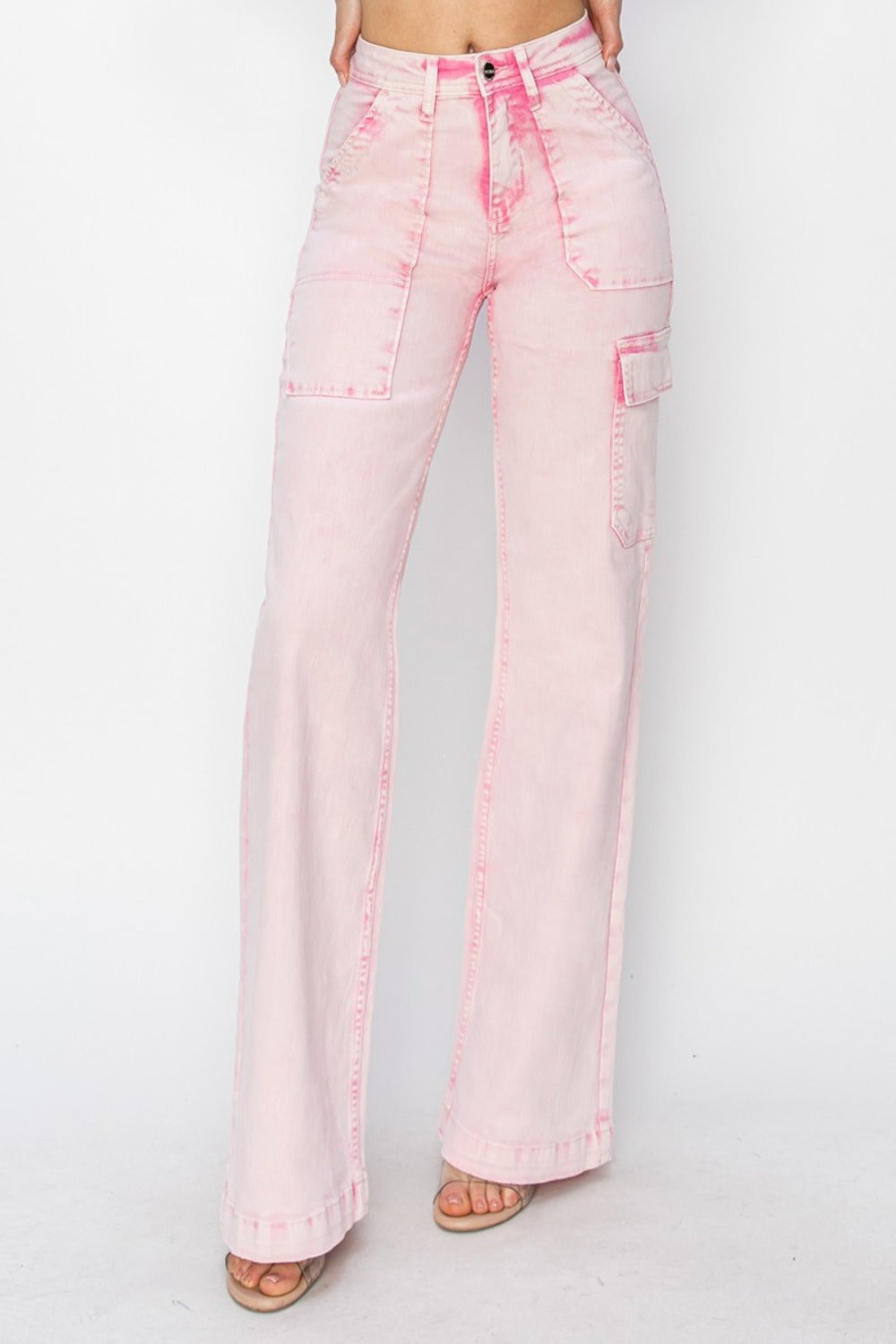 Person wearing the RISEN Full Size High Rise Wide Leg Cargo Pocket Jeans in light pink, featuring front pockets and a button-zip closure, standing against a white background.