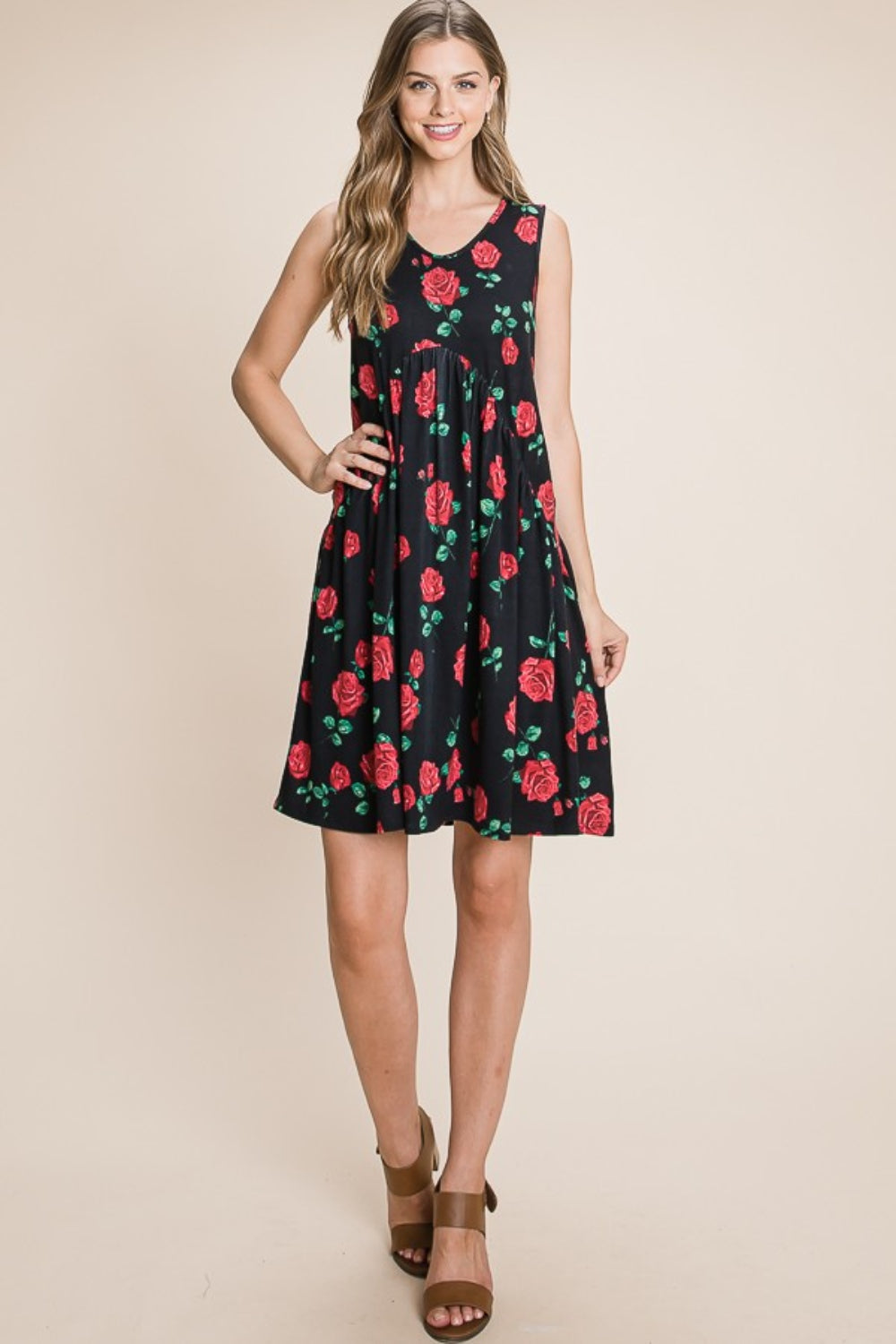 A woman is wearing a sleeveless BOMBOM Floral Ruched Tank Dress adorned with a black and red rose pattern. She is smiling and standing against a neutral background.