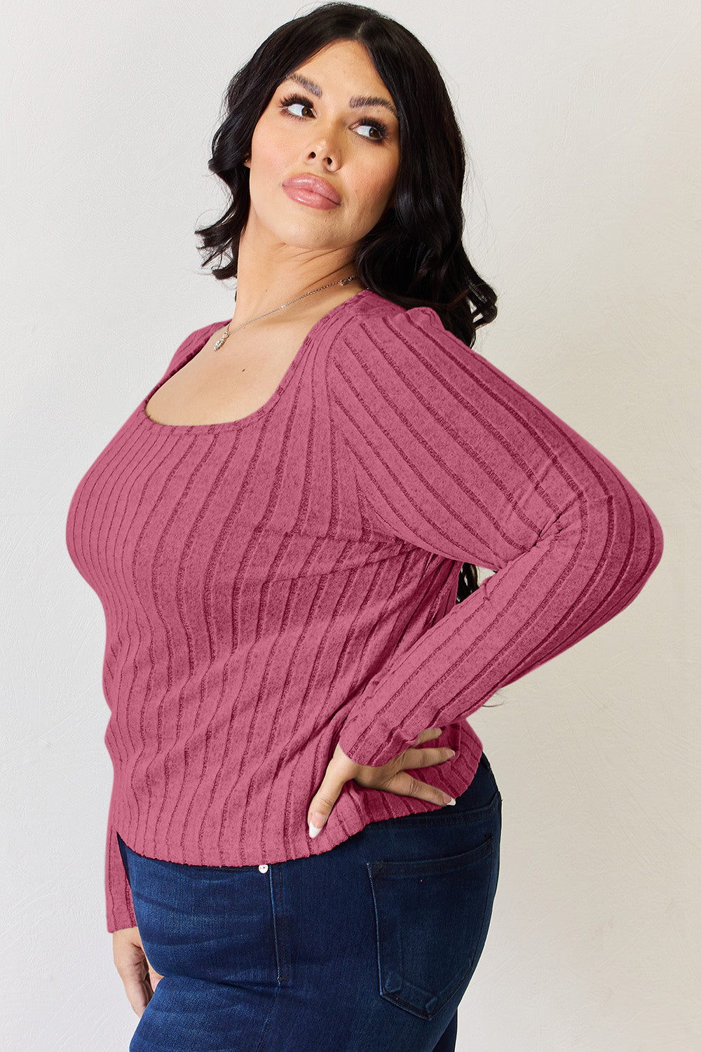 A person is standing and smiling, wearing the Basic Bae Full Size Ribbed Long Sleeve T-Shirt in light brown along with jeans. The basic style is perfect for any casual outing.