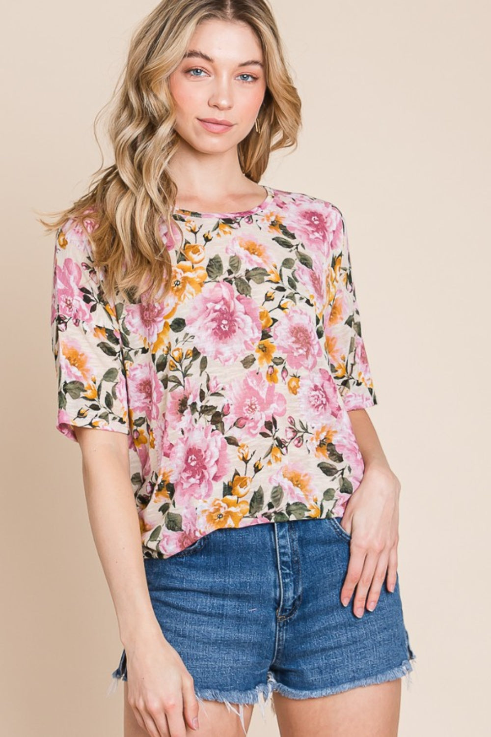 Wearing the BOMBOM Floral Round Neck T-Shirt and denim shorts, a person effortlessly embodies casual elegance against a plain beige background.