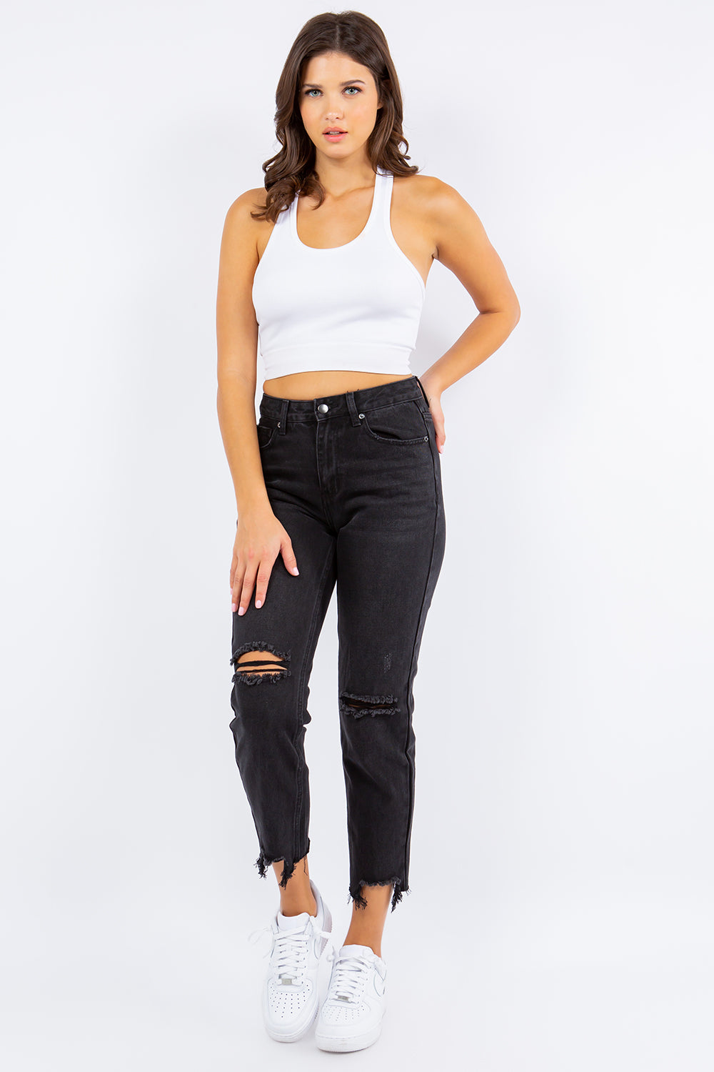 A person dressed in American Bazi High Waist Distressed Cropped Straight Jeans and white sneakers stands against a plain background.