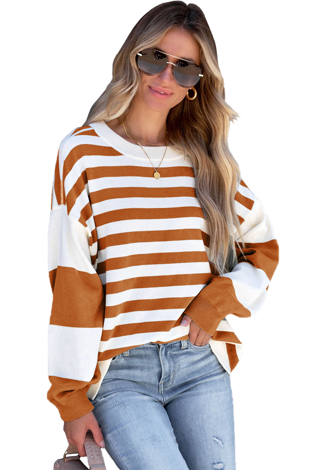 A person wearing sunglasses, gold earrings, a gold necklace, a Brown Stripe Drop Shoulder Striped Pullover Sweatshirt in white and orange stripes, and light blue jeans stands against a gray backdrop.