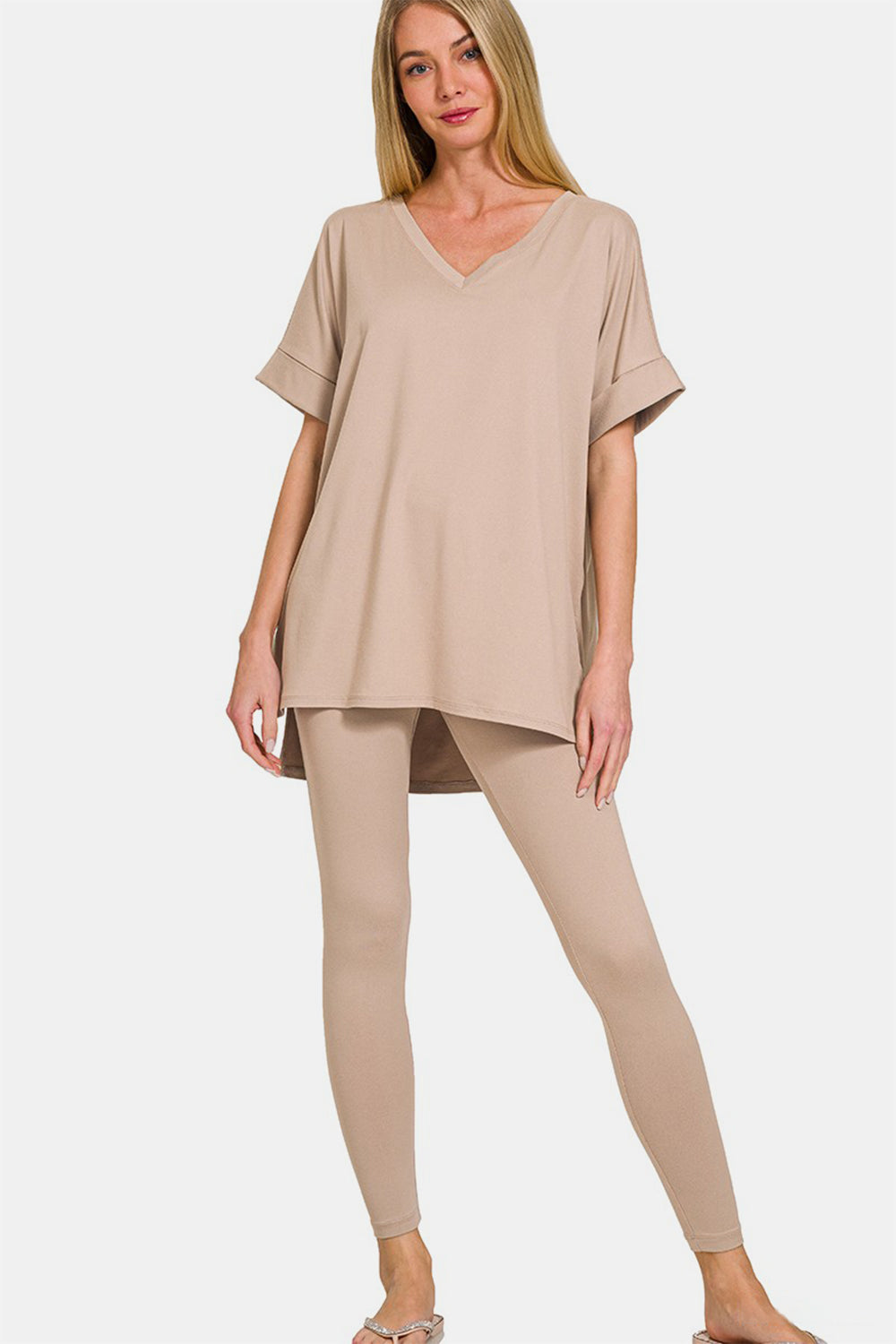 A person exudes comfort and style in the Zenana Full Size V-Neck Rolled Short Sleeve T-Shirt and Leggings Lounge Set, standing against a plain white background.