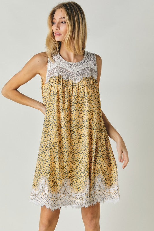 A woman wearing the Printed Sleeveless Lace Trim Mini Dress is seated against a light background.