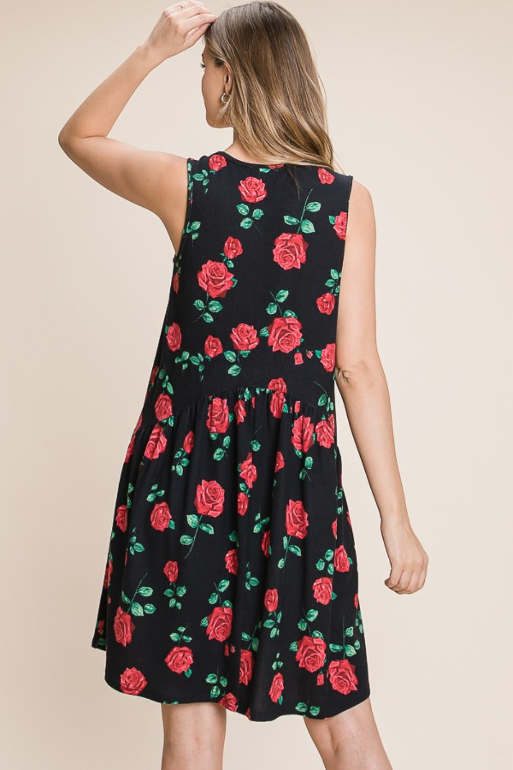 A woman is wearing a sleeveless BOMBOM Floral Ruched Tank Dress adorned with a black and red rose pattern. She is smiling and standing against a neutral background.