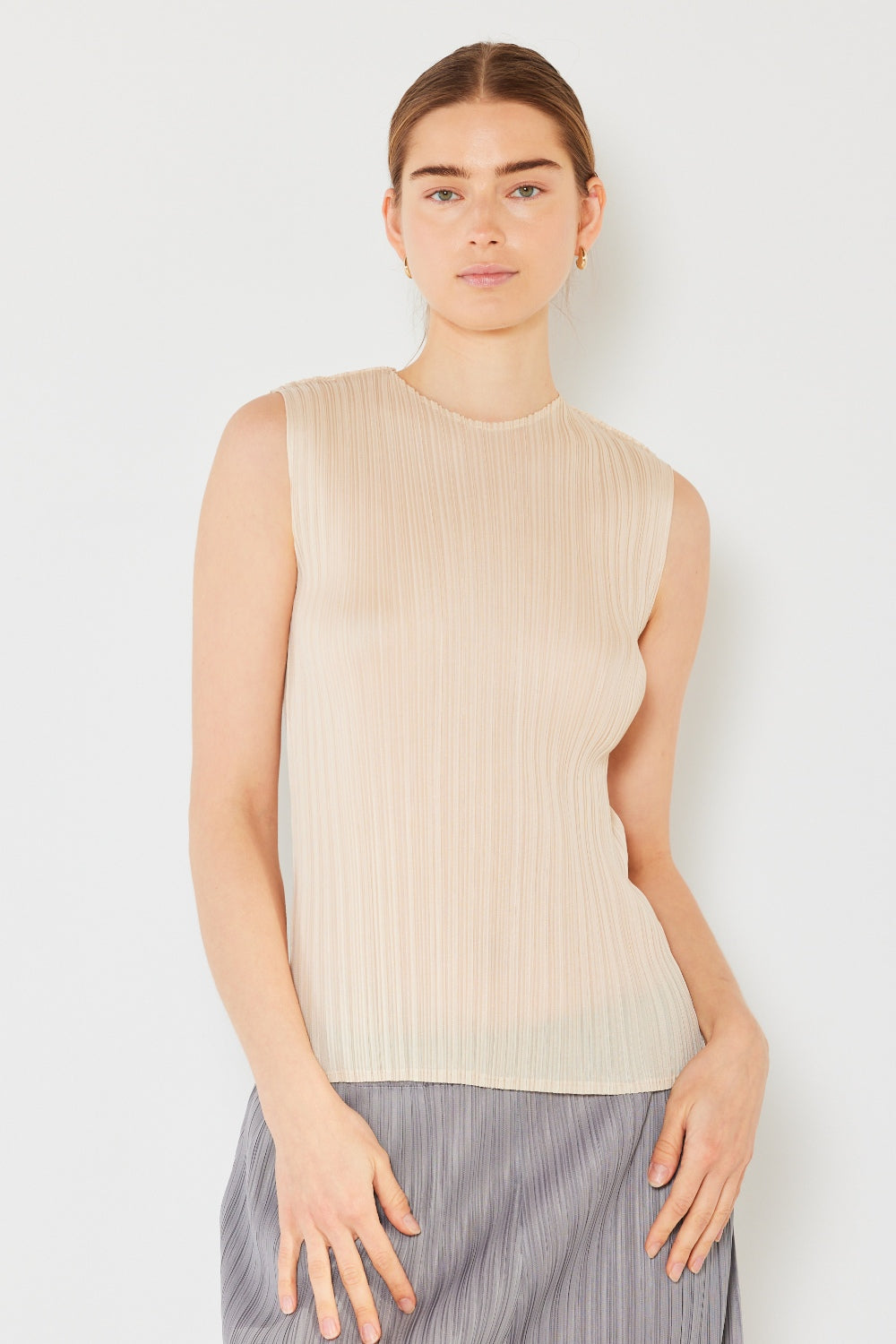 Person wearing a Marina West Swim Pleated Sleeveless Crewneck Tank and a gray pleated skirt, standing against a white background.