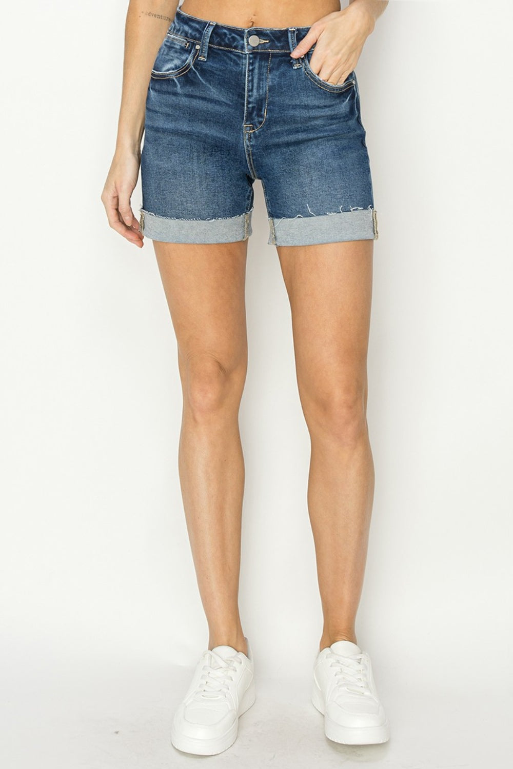 Person wearing RISEN High Rise Cuffed Denim Shorts with frayed hems, standing against a plain background. This chic and classic look is perfect for your summer wardrobe.