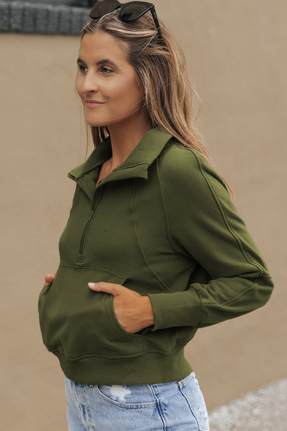 A person with long, wavy hair stands in front of a white and black background, wearing the Green Fleece Lined Zip Up Stand Collar Thumbhole Sleeve Sweatshirt paired with white shorts, creating a stylish look perfect for casual outings.