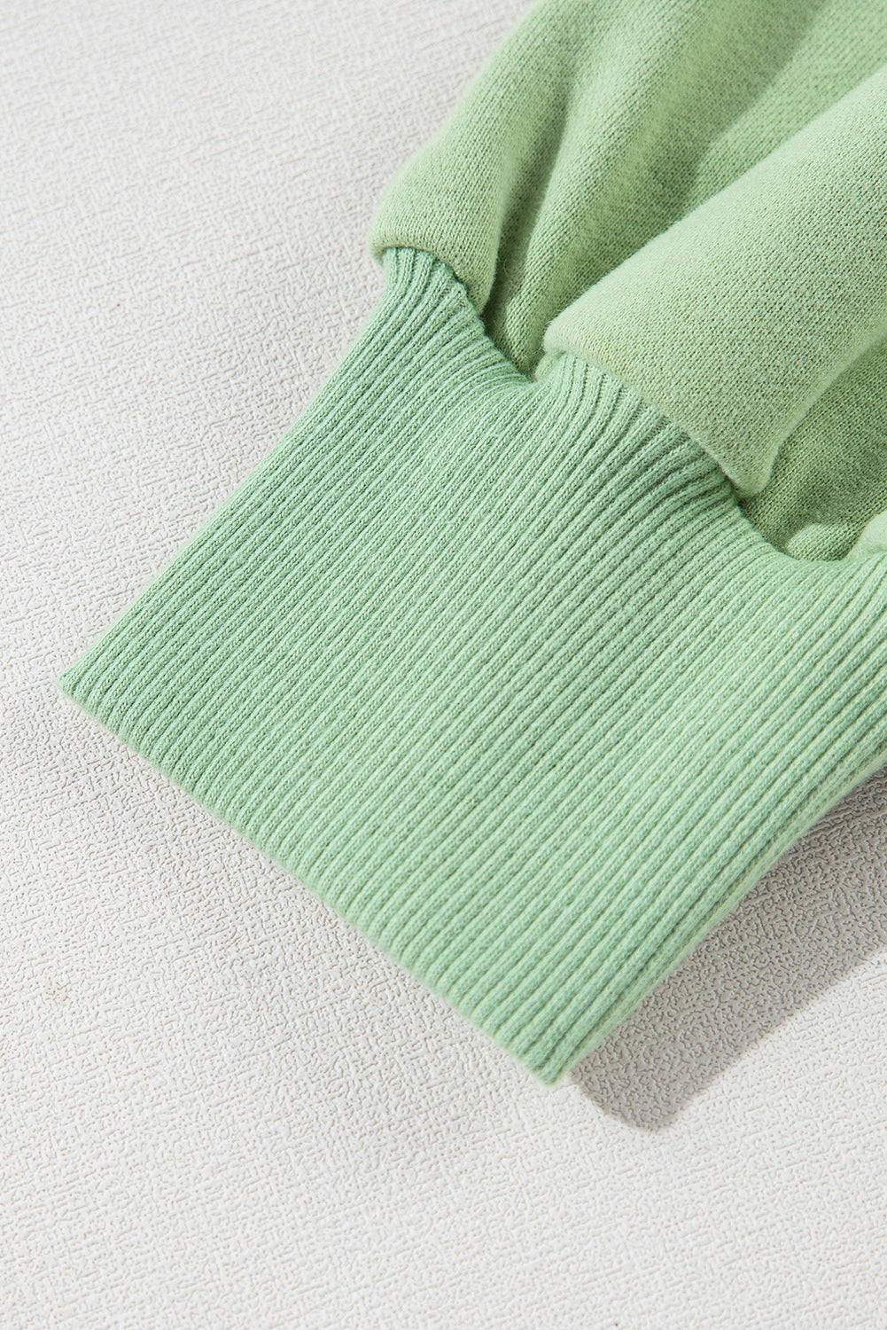 A person with long hair, seen from the back, wearing a Grass Green Solid Fleece Lined Drop Shoulder High Low Sweatshirt and black pants.