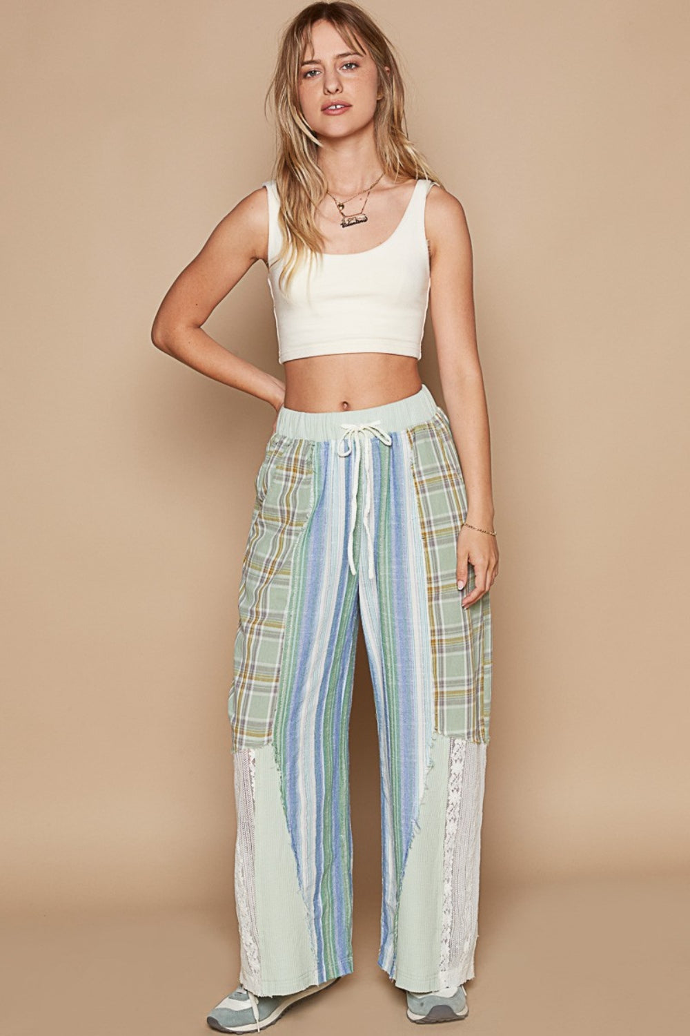 A person wearing a white crop top and POL Drawstring Plaid Print Lace Straight Pants, paired with gray and white sneakers.