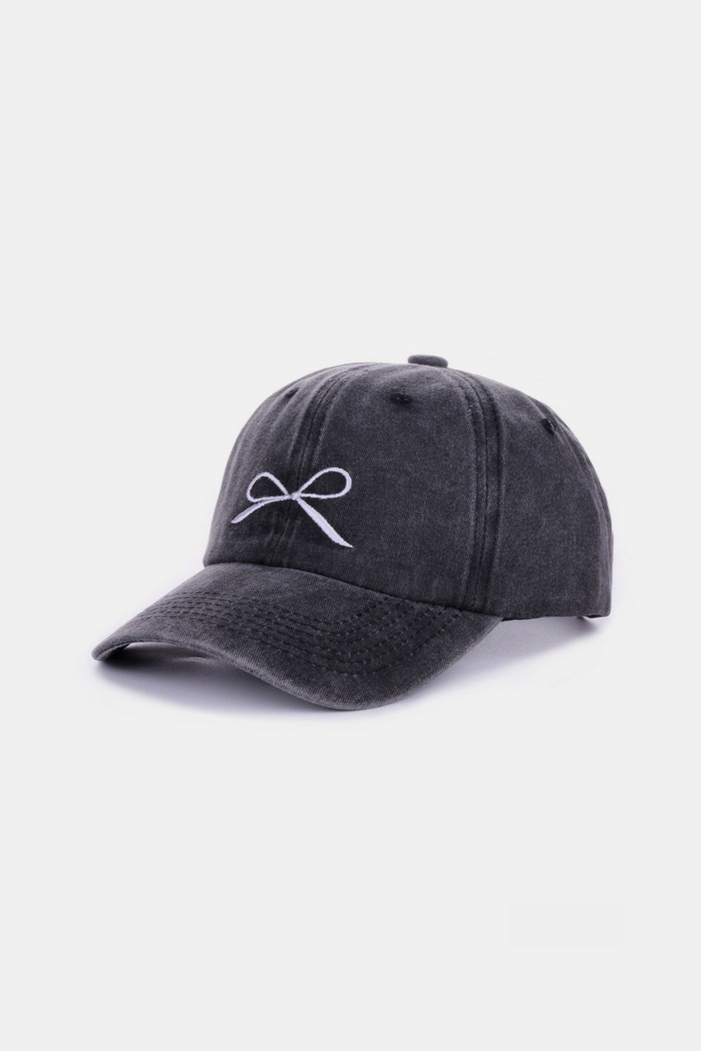 The Zenana Bow Embroidered Washed Cotton Cap features a pink design with a stylish white bow on the front, set against a plain, light background. This chic accessory seamlessly combines elegance and sportiness.