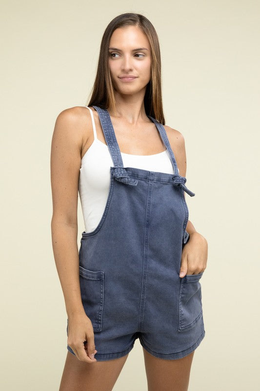 A person wearing the Washed Knot Strap Romper and a white tank top stands against a plain background.