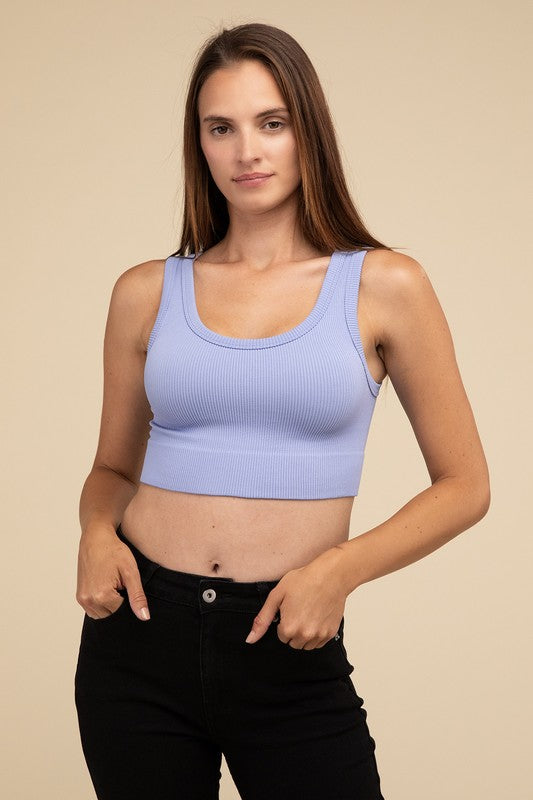 A person with long brown hair wearing the Ribbed Seamless Crop Top in light blue and black pants stands against a beige background, showcasing a perfect summer essential.