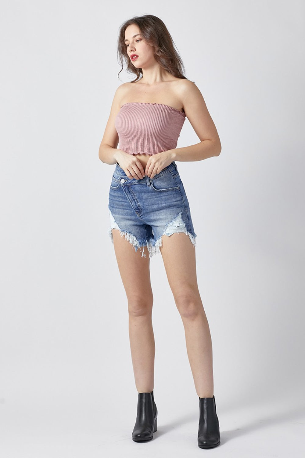 Close-up of a person wearing RISEN Raw Hem Asymmetrical Waist Denim Shorts with frayed hems—perfect for a fashion-forward summer wardrobe.