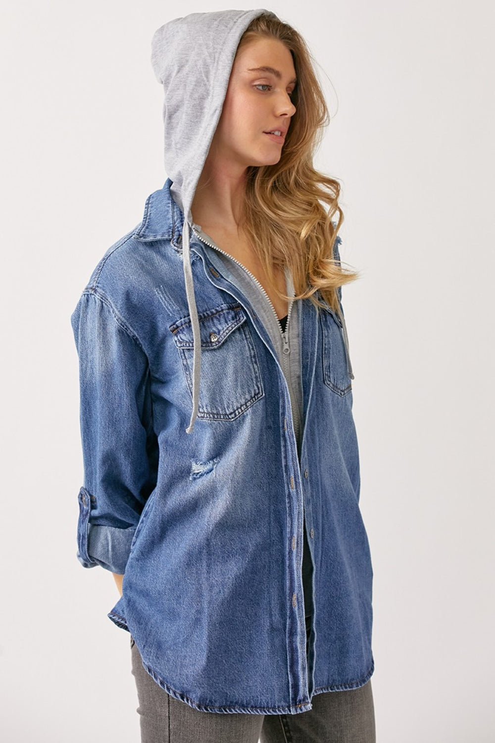 A person with long hair wears a casual oversized grey hooded sweatshirt under a RISEN Zip Up Hooded Denim Shirt.