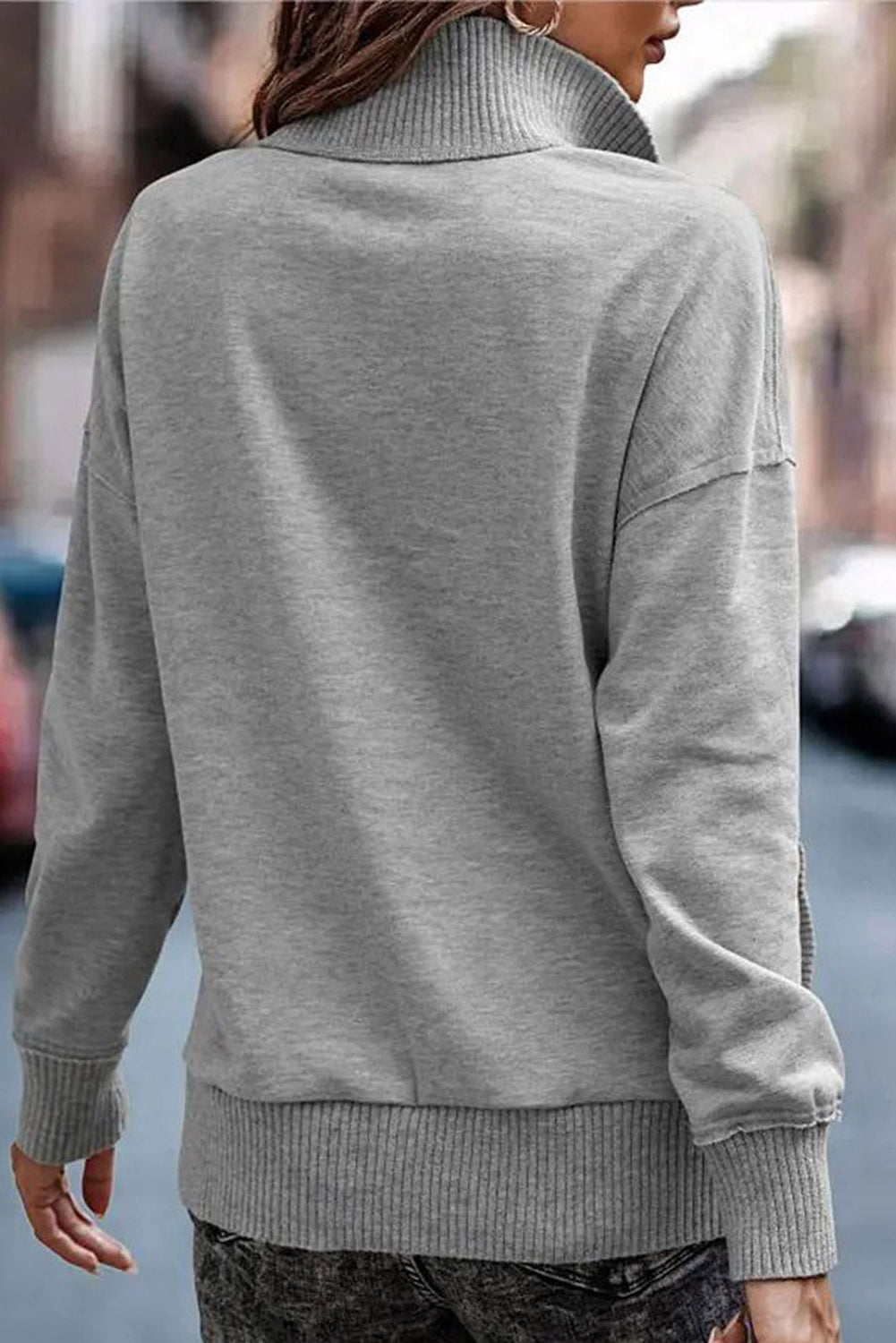 A person wearing a Gray Ribbed Hem Snap Button Neckline Sweatshirt with Pocket stands with their back to the camera on a city street.