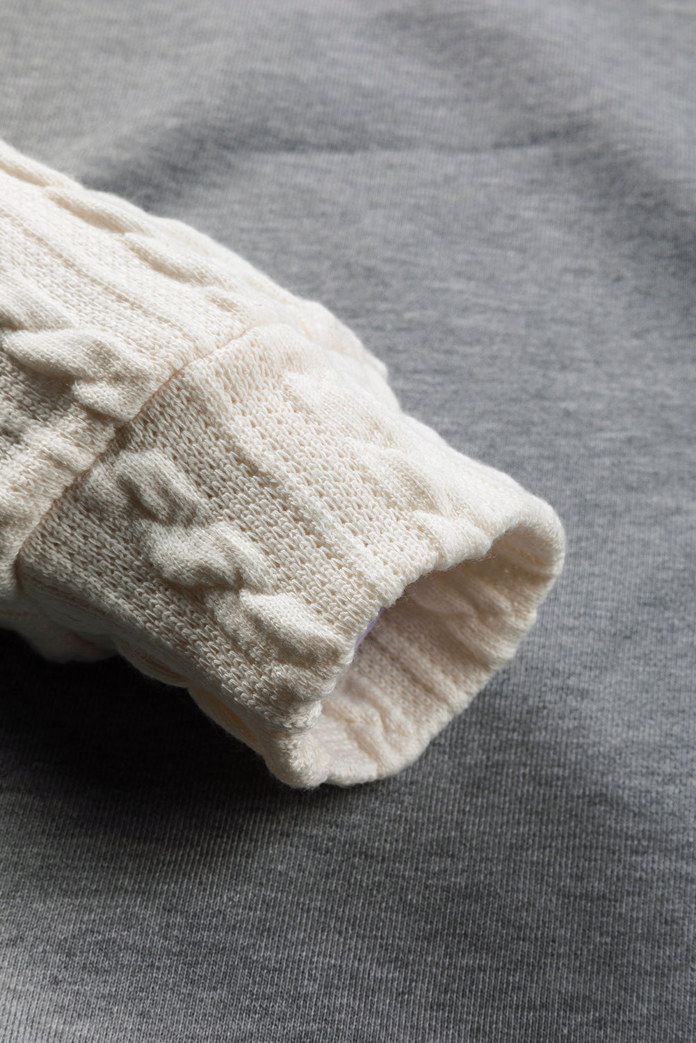 A person wearing a Dark Grey Cable Knit Sleeves Crew Neck Sweatshirt and a gold chain necklace is shown from the shoulders to the waist, standing outdoors.