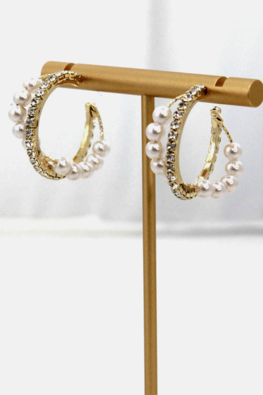 Alloy Pearl Hoop Earrings featuring gold hoops with imitation pearls and small clear gemstones, showcased on a vertical stand.