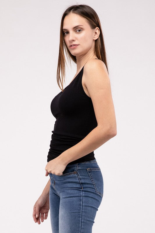 A woman in a white Front & Back 2-Way V-Neck Seamless Tank and black pants, standing with hands on hips and looking at the camera.