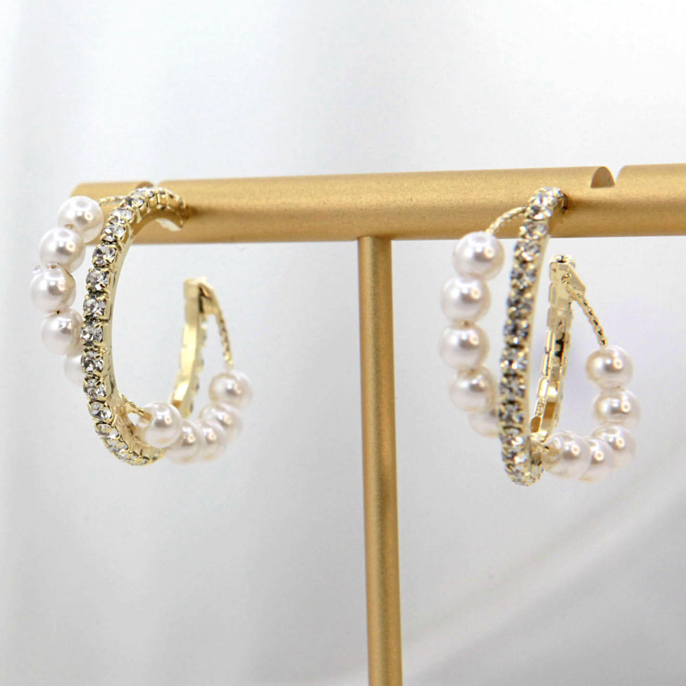 Alloy Pearl Hoop Earrings featuring gold hoops with imitation pearls and small clear gemstones, showcased on a vertical stand.