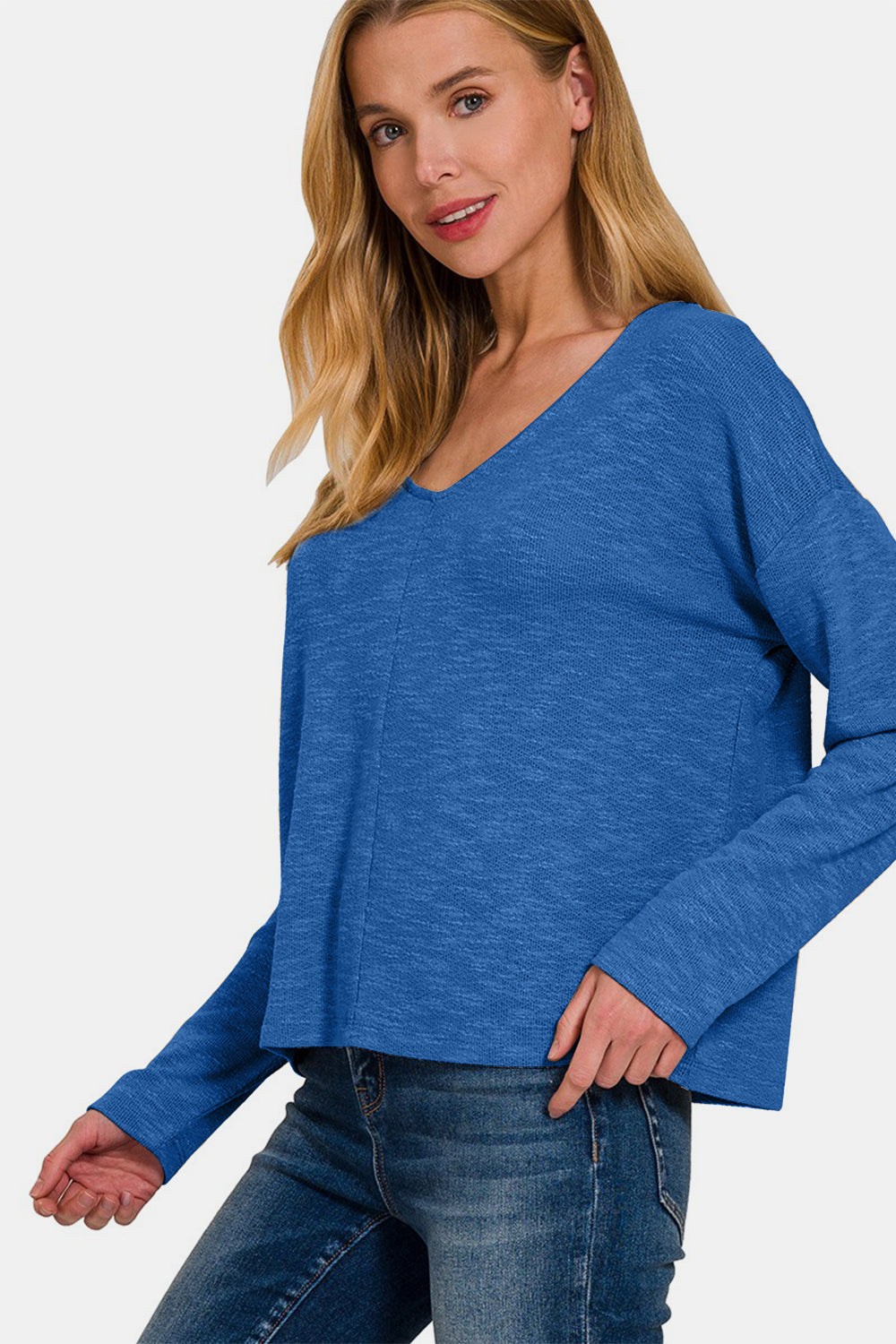 A person wearing a Zenana Dropped Shoulder Long Sleeve T-Shirt in blue and jeans stands against a plain background.