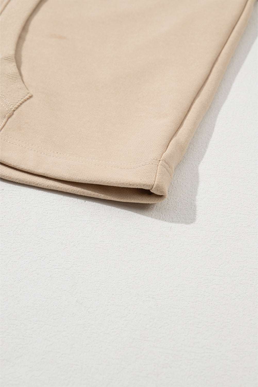 A person with long brown hair is standing with their back to the camera, wearing a Parchment Solid Kangaroo Pocket Half Zipper Oversized Hoodie and black shorts.