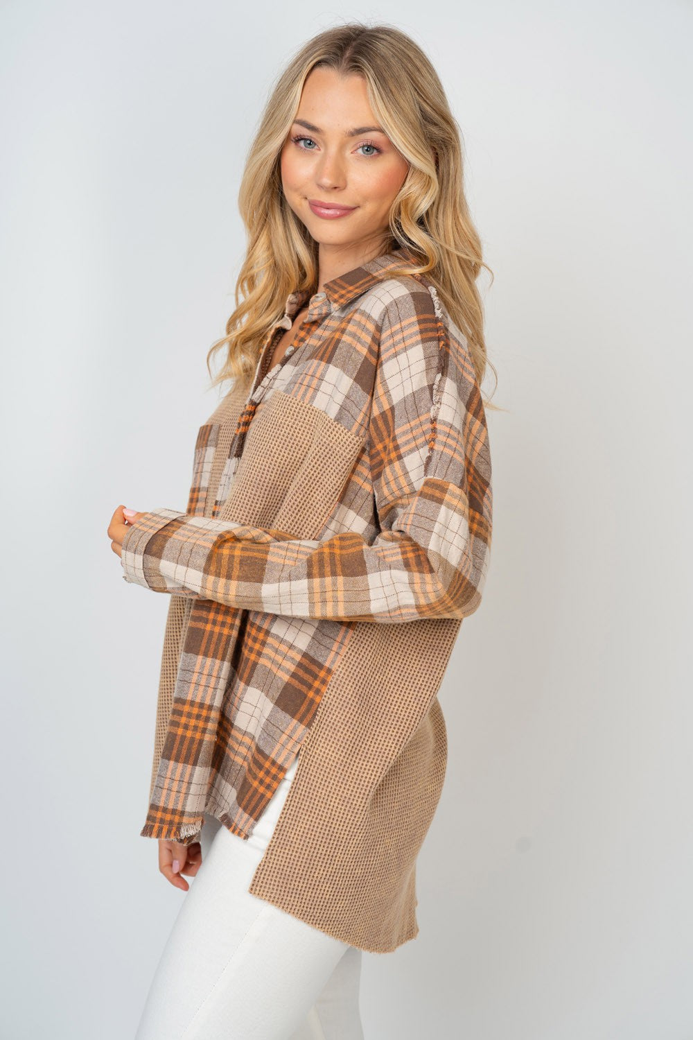 A person with long, blonde hair smiles while wearing the White Birch Full Size Contrast Plaid Button Down Shirt in beige, brown, and white hues, paired with white pants.
