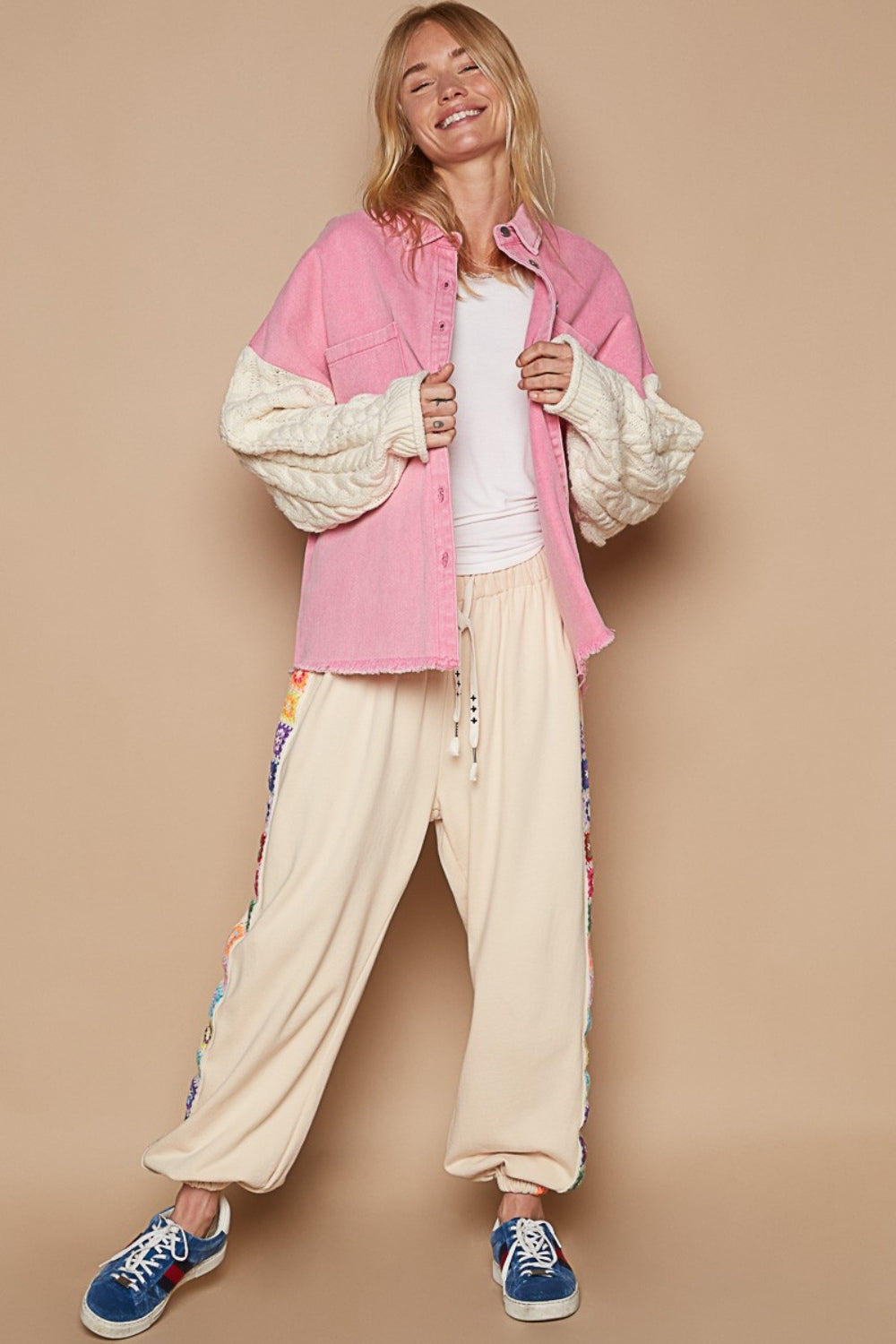 A trendy outfit showcases the POL Contrast Sweater Sleeve Button Down Shacket in pink, complete with knitted white sweater sleeves, paired with beige pants and set against a subtle beige background.