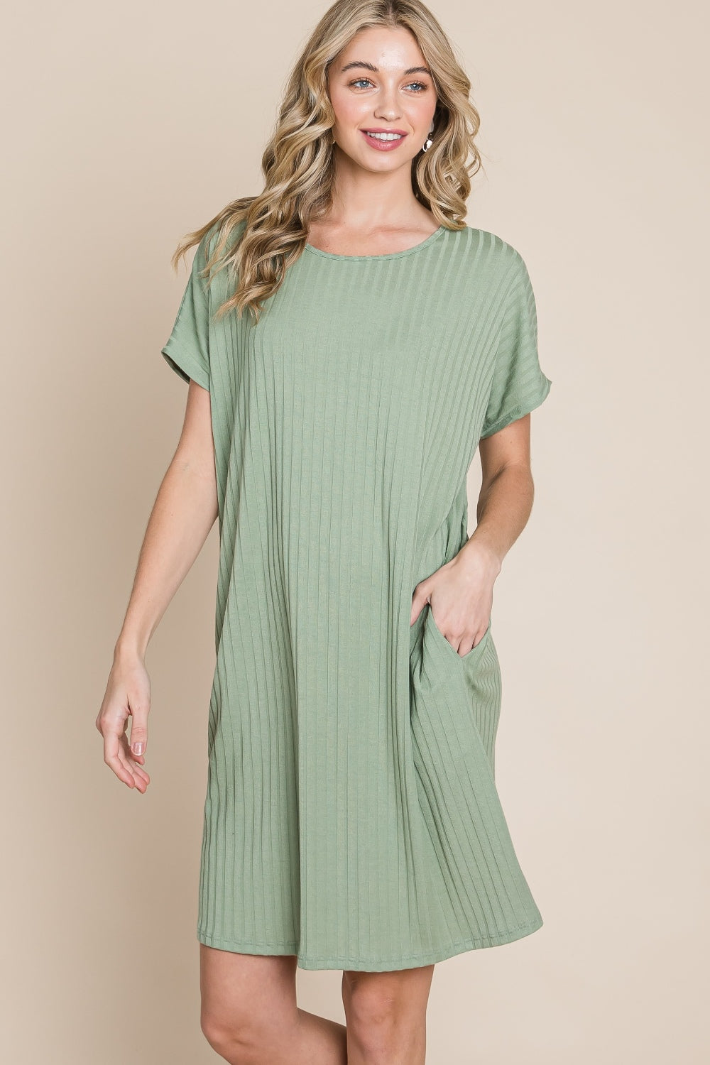 Against a beige background, a person is dressed in the BOMBOM Ribbed Round Neck Short Sleeve Dress in green, featuring a pocket.