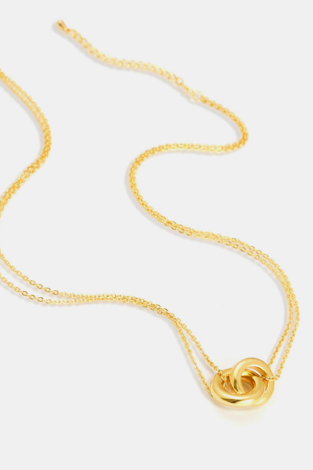 The Linked Ring Pendant Chain Necklace showcases an elegant design with a gold pendant featuring two interlocking circles.