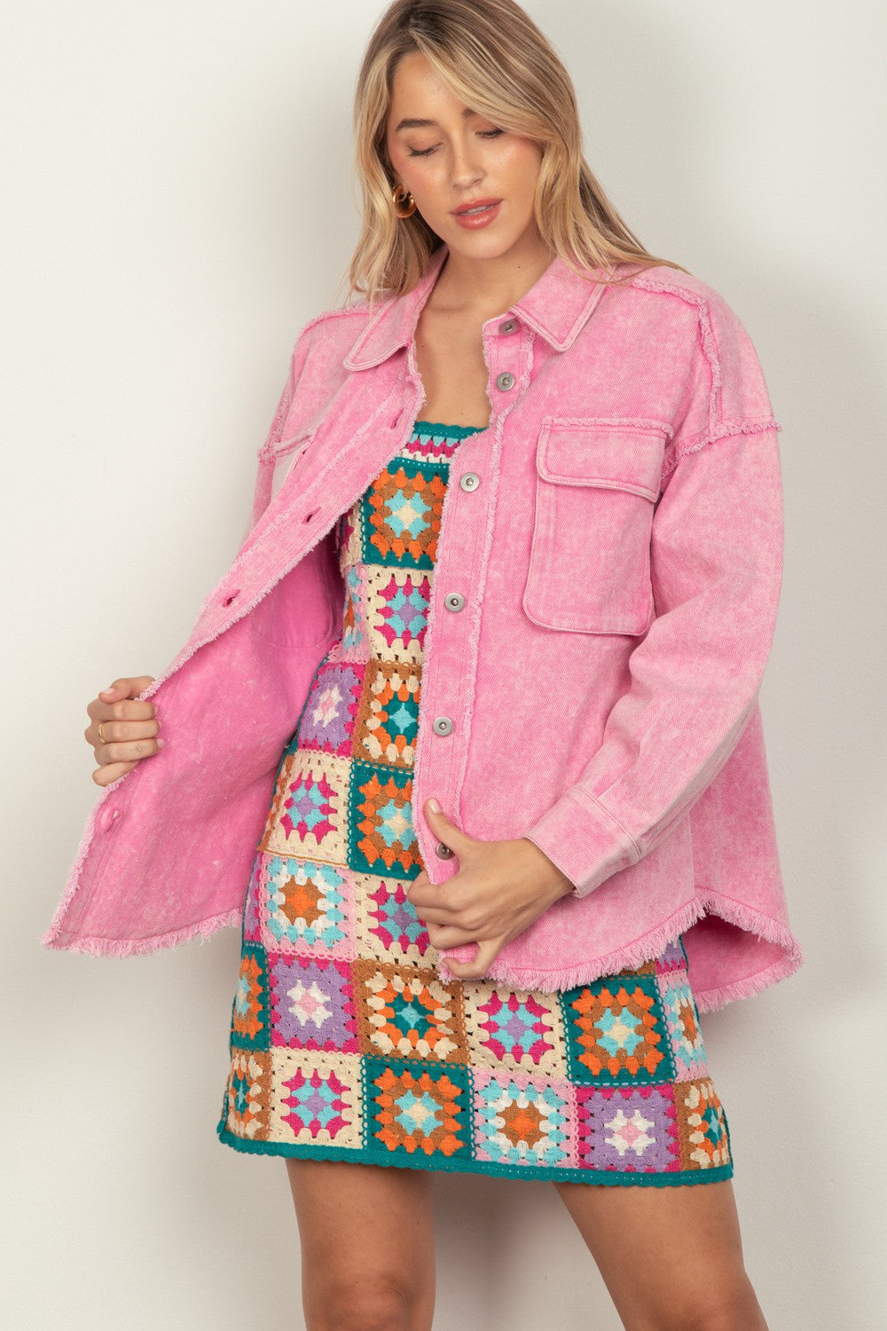 Person wearing a VERY J Full Size Button Up Raw Hem Long Sleeve Jacket in pink over a colorful, patterned dress, standing against a plain background.