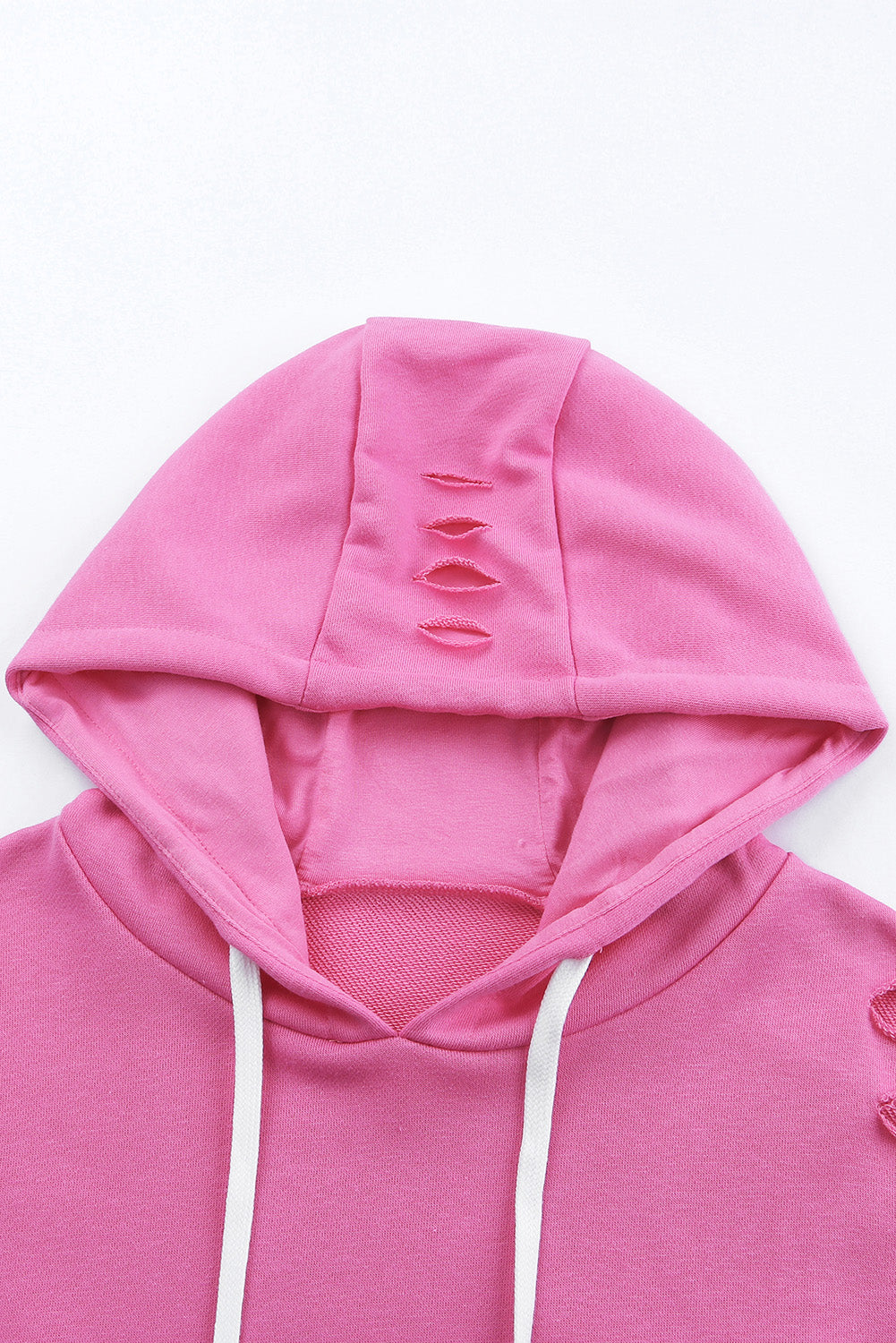 A person wearing a Pink Solid Ripped Hooded Sweatshirt with a Kangaroo Pocket is standing in front of a door.