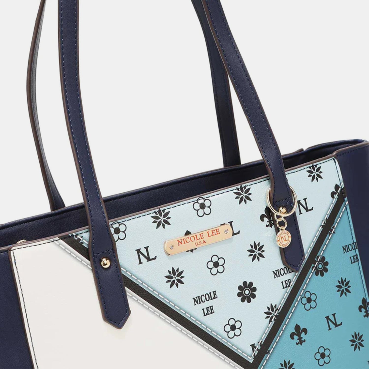 The Nicole Lee USA 3-Piece Color Block Handbag Set is a stylish collection that includes three blue and white vegan leather bags with black straps: a versatile tote bag, a chic small handbag, and an elegant round wristlet with a strap.