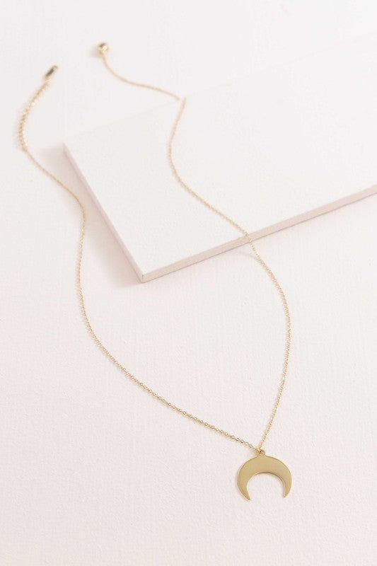 A delicate Moonglade Necklace 14K Gold with a crescent moon charm pendant displayed on a white surface.
