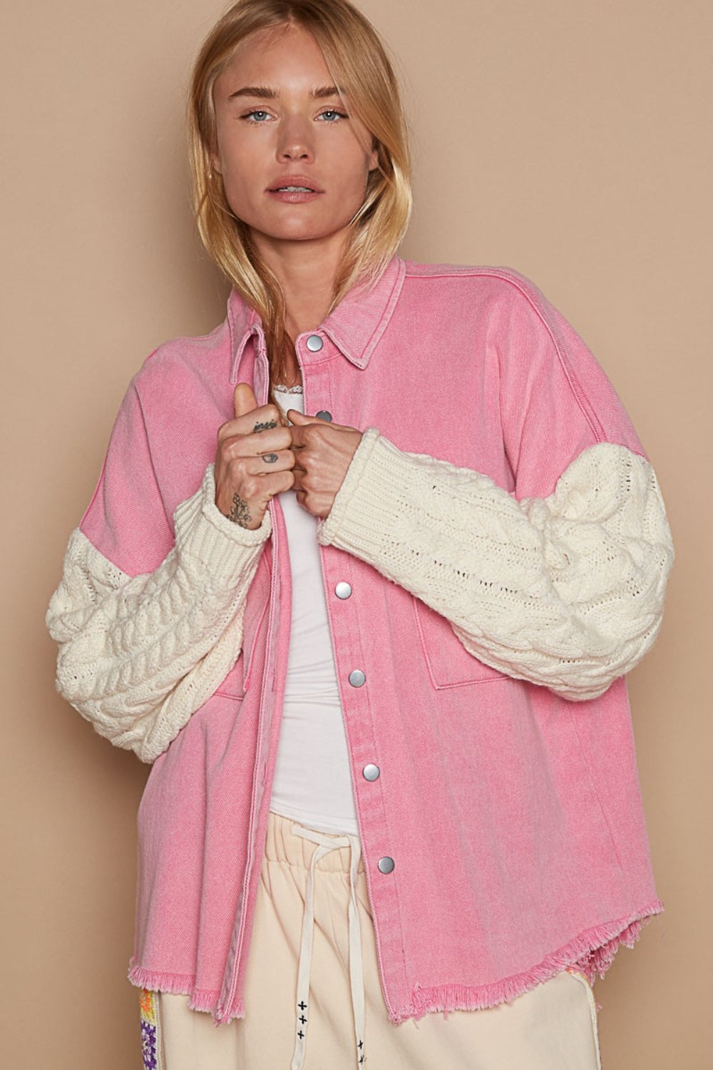 A trendy outfit showcases the POL Contrast Sweater Sleeve Button Down Shacket in pink, complete with knitted white sweater sleeves, paired with beige pants and set against a subtle beige background.