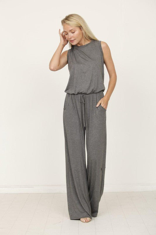 A person poses indoors against a white background, wearing the Plus Solid Drawstring Pocket Jumpsuit in a sleek olive green, crafted from soft rayon with a stylish drawstring detail.