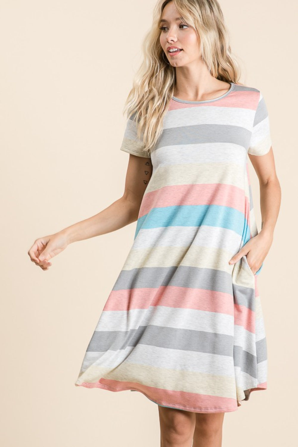 A woman is wearing the BOMBOM Striped Short Sleeve Dress, showcasing multicolored patterns and practical pockets for a casual look.