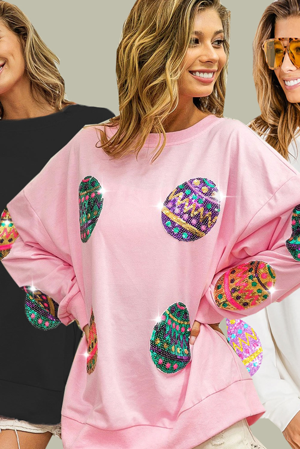 A woman with long, wavy hair wears a Pink Sequined Easter Egg Drop Shoulder Oversized Sweatshirt featuring colorful, patterned circles. She is seated in a dining area with a table set with glasses, plates, and two bottles, one of which is orange.