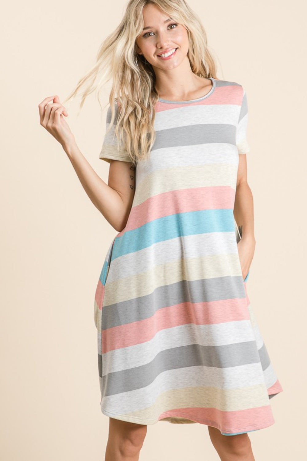 A woman is wearing the BOMBOM Striped Short Sleeve Dress, showcasing multicolored patterns and practical pockets for a casual look.