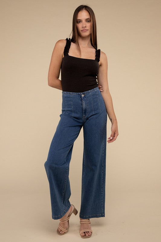 A young woman in a chic Ribbed Ruffle Strap Bodysuit and ripped denim shorts poses against a plain background.