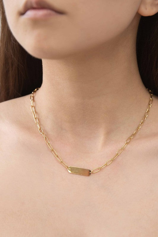 Plate Oval Chain Necklace showcases a bar pendant and sleek toggle clasp, plated with 14k gold on high-quality stainless steel against a light background.