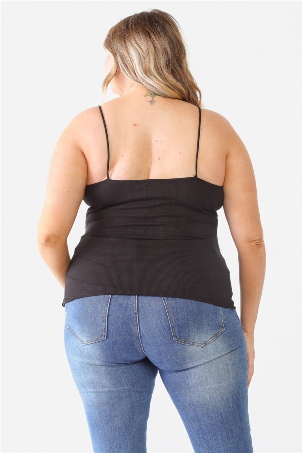 A person with long hair is wearing a Zenobia Plus Size Lace Detail V-Neck Cami and distressed jeans against a plain background.