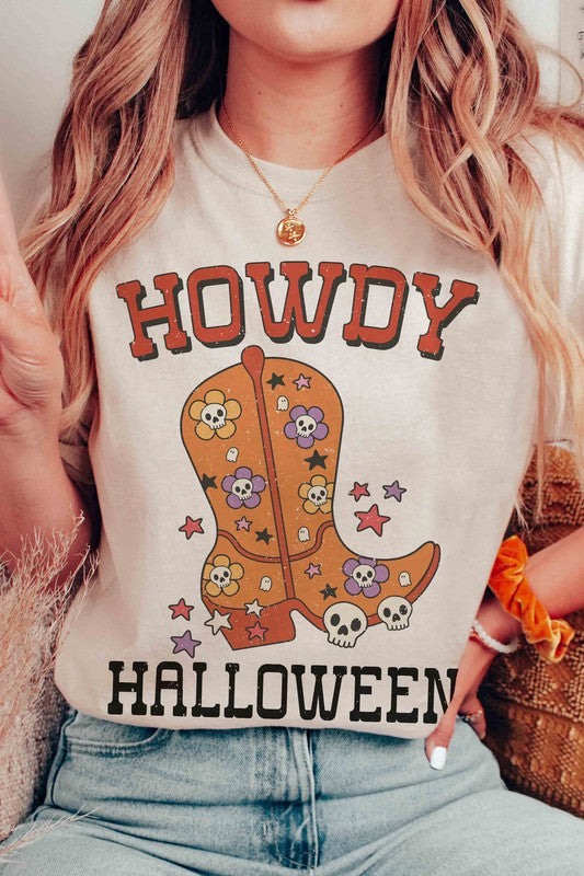 Person wearing the HOWDY HALLOWEEN Graphic Tee, a 100% cotton white t-shirt featuring the words "Howdy Halloween" along with a decorative boot embellished with skulls and flowers.