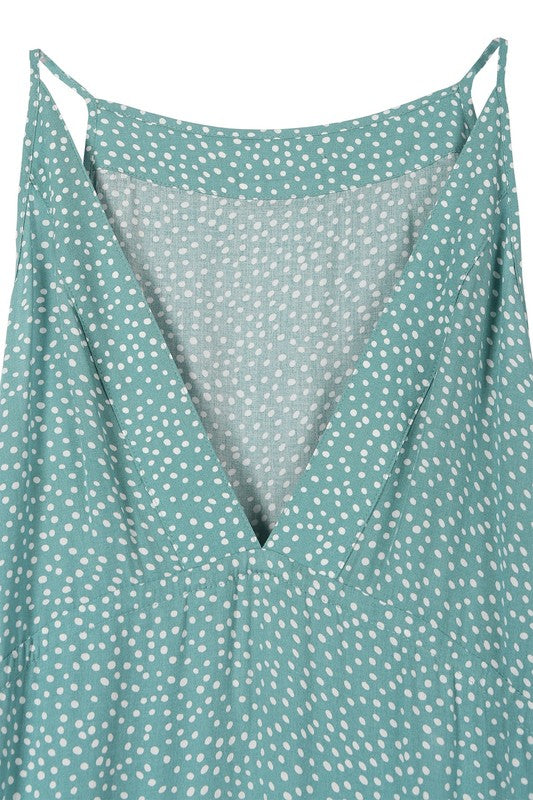 A woman with long blonde hair stands against a neutral background wearing the SL V neck tier dress, which features a teal color and polka dot pattern.