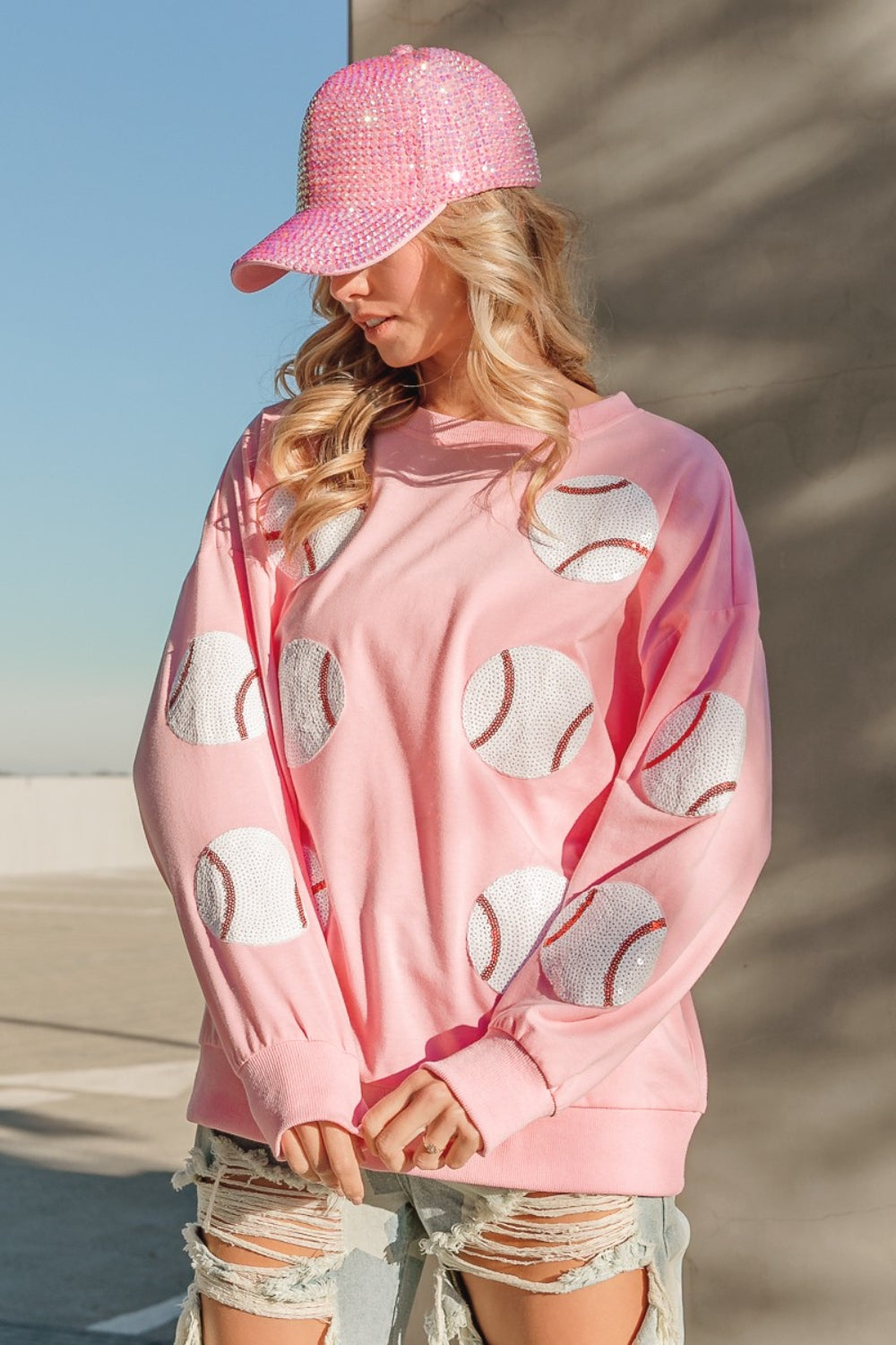 Person wearing a trendy and eye-catching pink sequin cap and the BiBi Sequin Baseball Patches French Terry Sweatshirt, standing in outdoor daylight.