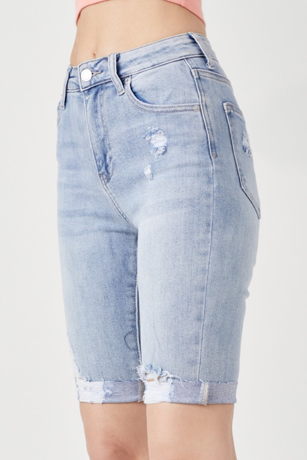 Person wearing RISEN High Rise Distressed Denim Bermuda Shorts with rolled cuffs, showcasing a flattering silhouette against a plain background—giving a trendy twist to classic denim.